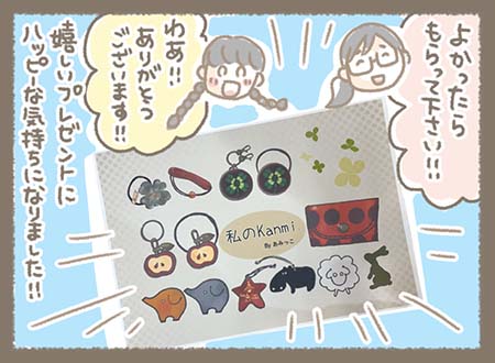 お客様が描いたKanmi.のバッグや財布、小物などのイラストが並んだ作品を前に、**スタッフが「わぁ!!ありがとうございます!!」と感激すると、お客様は「よかったらもらって下さい!!」と作品をプレゼント。スタッフは思いがけない贈り物に感激し、「嬉しいプレゼントにハッピーな気持ちになりました!!」と心温まる出来事